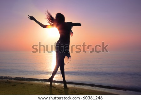 Silhouette of the woman dancing at the beach during beautiful sunrise. Natural light and darkness. Artistic vivid colors added