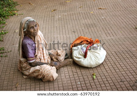 Beggar Indian woman sitting on the street and beging alms. Natural light and colors