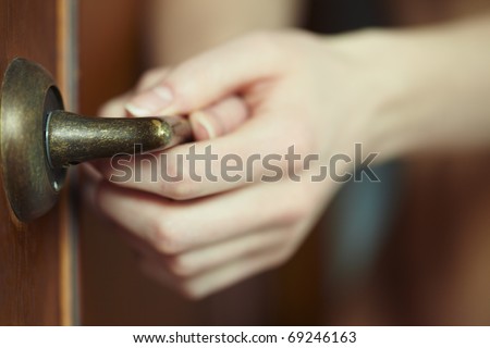 Close-up photo of the human hands holding door handle. Shallow depth of field added by the lens for natural view