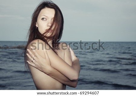 Single lady at the sea with hair blown by the wind. Natural light and colors