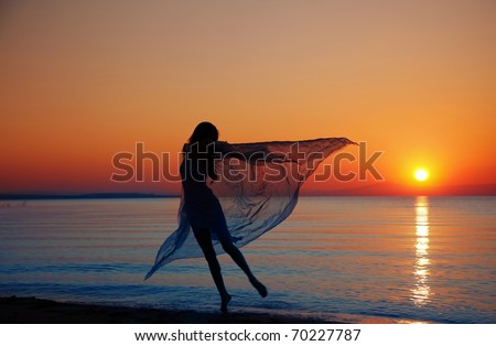 Silouette of the nifty woman dancing at the sea during sunset. Natural light and darkness. Artistic colors added
