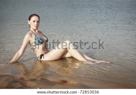 Lady in bikini laying in the water of paradise beach. Natural light and colors