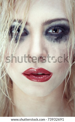 Crazy sad lady with bizarre dirty makeup. Close-up portrait