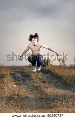 Angry topless muscular man outdoors jumping. Artistic colors added