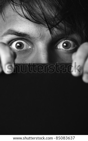 Afraid human hiding behind the dark board. Monochrome photo. Film noir effect added