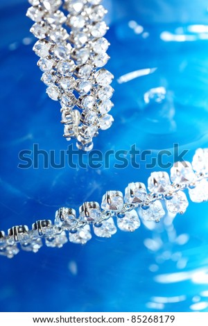 Close-up photo of the silver necklace with diamonds on a blue background with bokeh