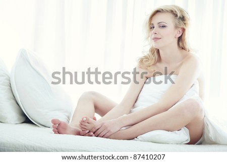 Blond lady sitting on the bed in spa room