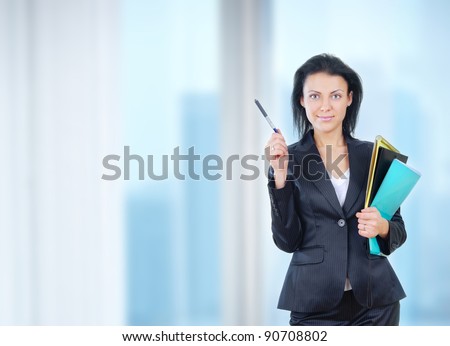 Successful businesswoman stands in office with documents and pen