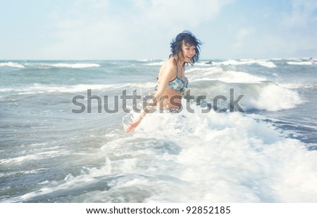 Happy brunette lady laughs and plays with water at summer beach