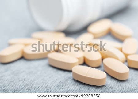 Many pills of antibiotic near white container. Close-up photo
