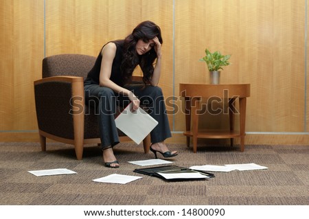 Frustrated business women in office lobby, with paper mess.
