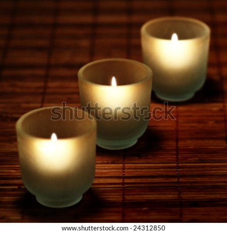 Candles burning at night on top of bamboo mat.