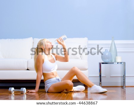 Side view of a young woman drinking bottled water after exercising.  Horizontal shot.