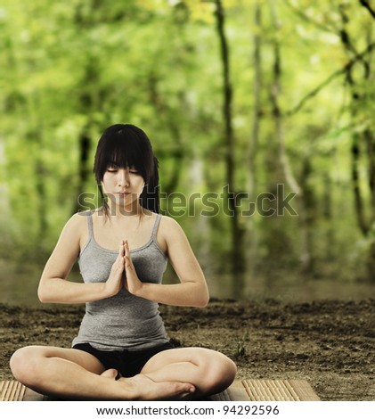 Asian woman on a yoga mat doing the salutation seal pose in a forest. Meditation.