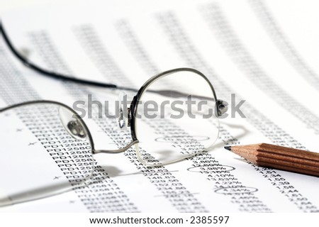 Sales Report in listform with marked data, brown pencil and eyeglasses