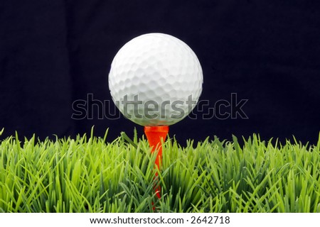 white golfball in orange tee, green fairway, isolated on black background