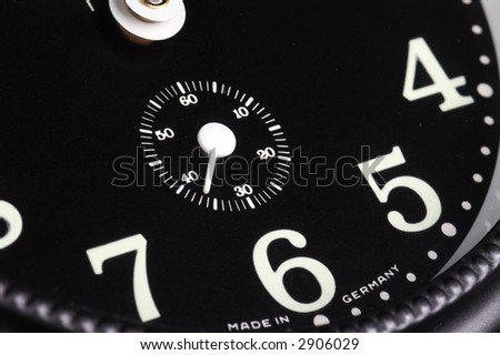Old alarm clock on black background with black clock face and white needles - landscape format