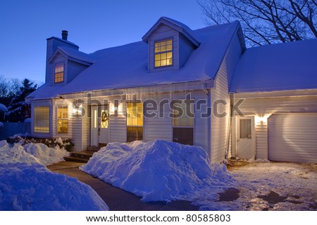 Typical American home with icy winter snow - evening twilight - cape cod style