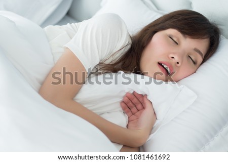 tired exhausted stressed woman snoring; portrait of stressful, exhausted woman snoring while sleeping on bed in bedroom environment; health, mental care medical concept; asian adult woman model