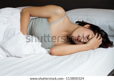 sick woman on bed concept of stomachache, headache, hangover, sleeplessness or insomnia