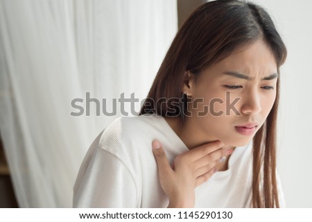 sick woman with sore throat; portrait of woman suffering from cold, flu, sickness with sore throat inflammation; woman health care, body care, sickness, pain concept; asian young adult woman model