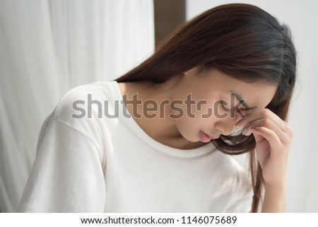 portrait of stressed sick woman with headache; depressed woman suffers from vertigo, dizziness, migraine, hangover; health care concept; 20s young adult asian middle east, mixed race woman model