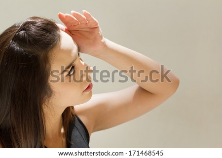 woman suffers from heat of strong sunlight, plain background
