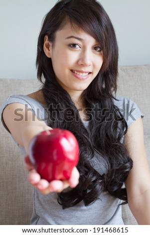 healthy woman with red apple, mixed race asian caucasian indoor scene