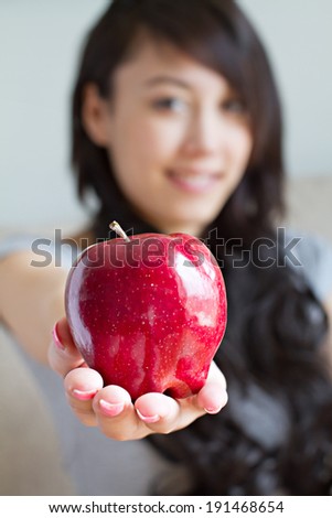 healthy woman with red apple, mixed race asian caucasian indoor scene