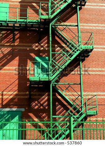Red brick wall with green metal stairs