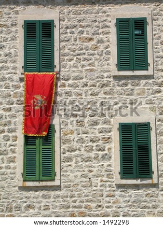 Stone wall with windows, green shutter and Montenegro flag