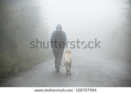 Young man with his labrador on trip in mystery fog.