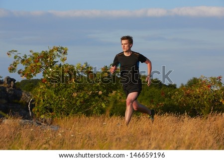 Young man is running in nature - selective focus