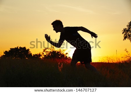 Silhouette of young man at the sunset - back lit
