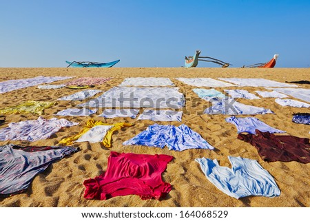 Washed clothes are drying on the beach.