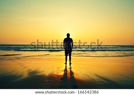 Silhouette Of Young Man On The Beach At Sunset.