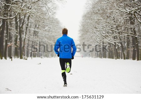 Young runner in winter jogging in park.