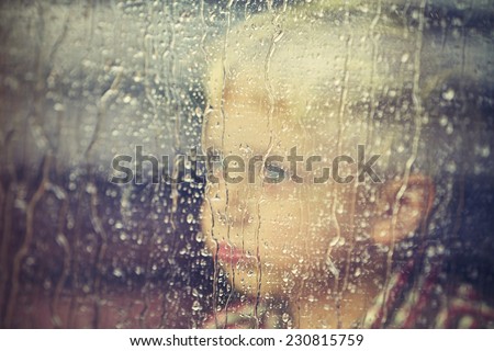 Little boy behind the window in the rain - selective focus