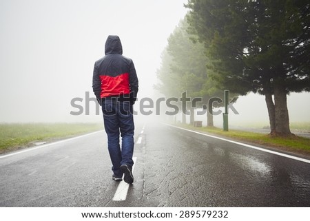 Lonely man is walking in mysterious fog