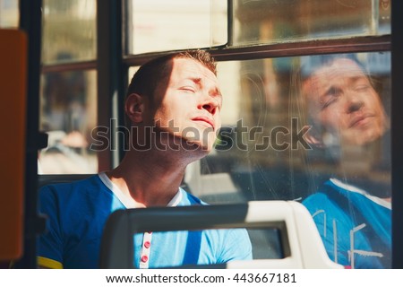 Everyday life and commuting to work by public transportation. Handsome young man is traveling by tram (bus). Tired man in hot day. Prague, Czech Republic