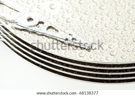 Open hard drive disk with water drops and focused on magnetic head.