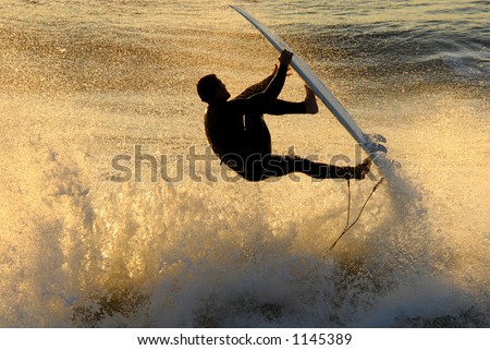 A backlit surfer catches air against the warm colors of the setting sun.