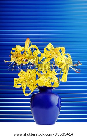 bouquet of yellow lilies in the blue jar on a background of blue shutters