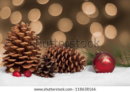 Pine cone and ornaments in snow with christmas lights background