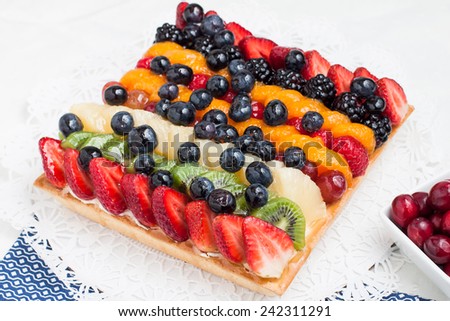 A fresh fruit tart viewed from above with bowl of fresh berries