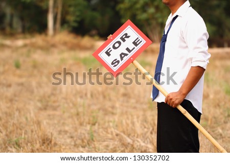 Man holding a sign land for sale.