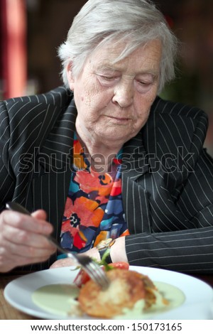 Elderly woman eating in restaurant