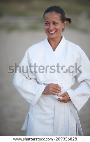 Portrait of beautiful smiling tanned woman in kimono;woman in martial art
