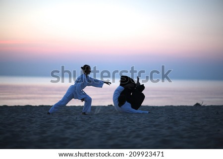 Woman practicing Martial arts on the beach at sunset