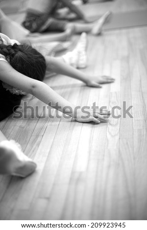 Small girls stretching on the floor, gymnastic exercises; monochrome